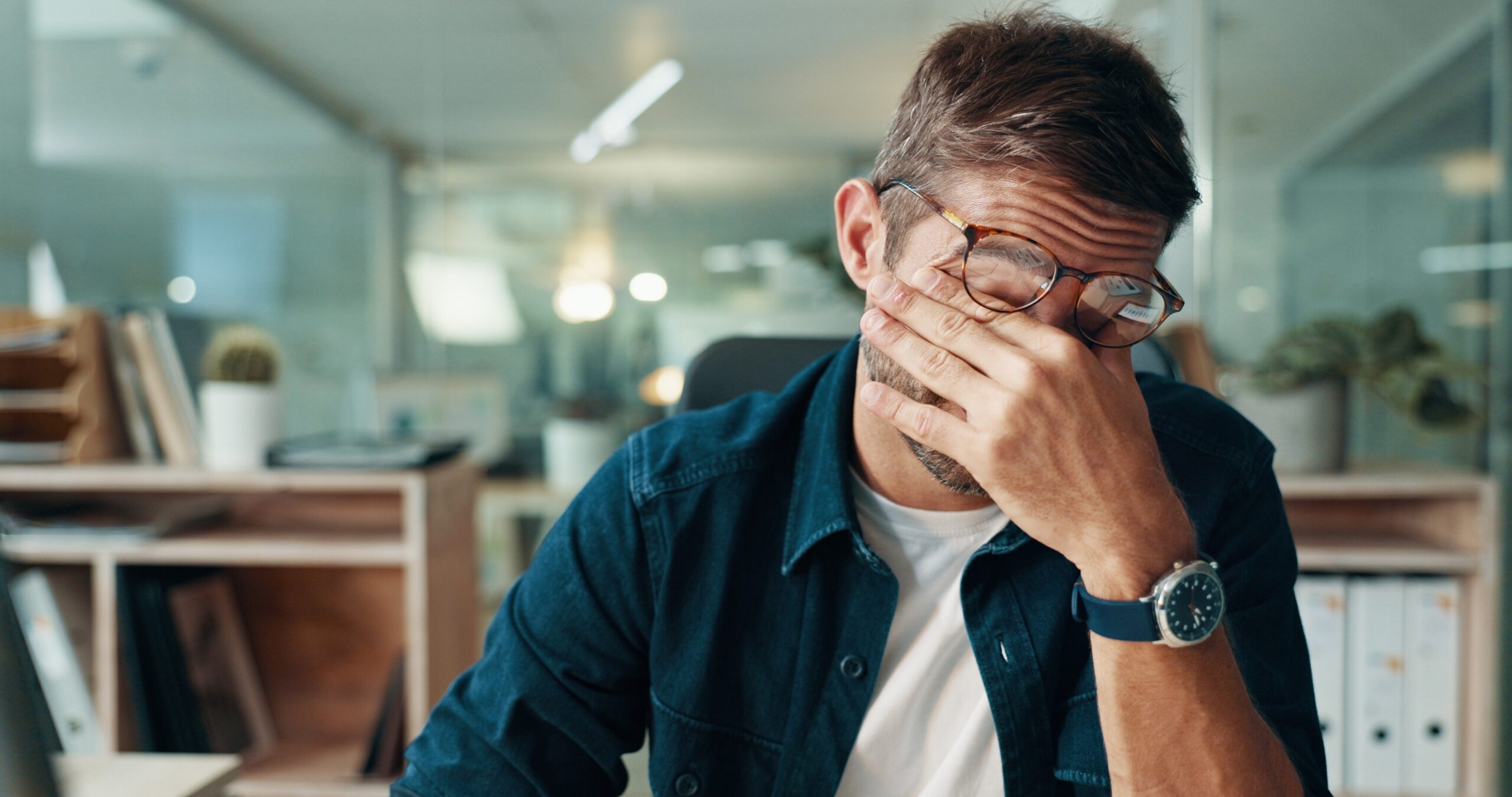 man covering his face with hand, suffering from TMJ headaches