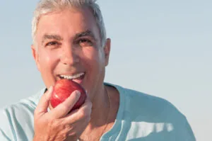 Man biting apple with restored bite force from bite adjustment.