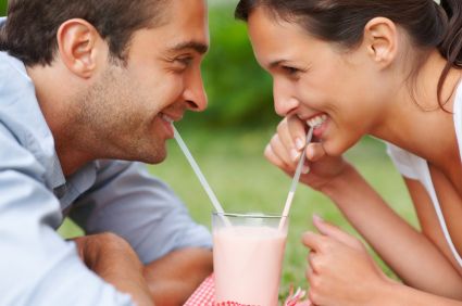 A young couple smiling over a milkshake after teeth whitening in Elgin.