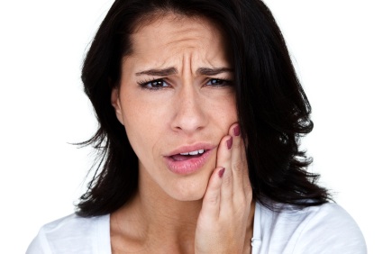 A young woman clutching her jaw from pain caused by untreated TMJ in Elgin.